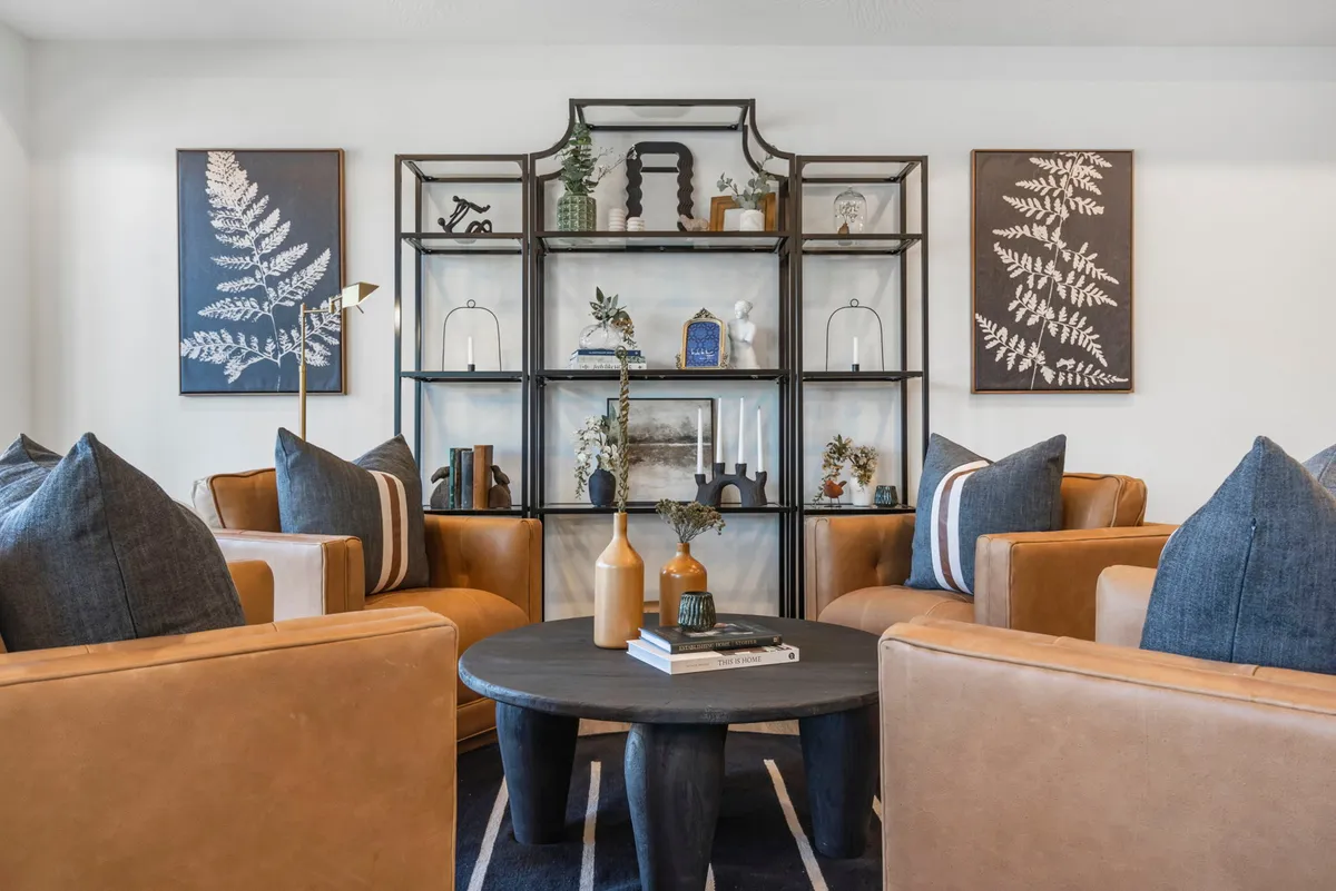 The image showcases a beautifully decorated living area with inviting armchairs around a stylish coffee table and shelves adorned with tasteful décor. The space exudes comfort, warmth, and is ideal for relaxing, socializing, or cozying up with a book.