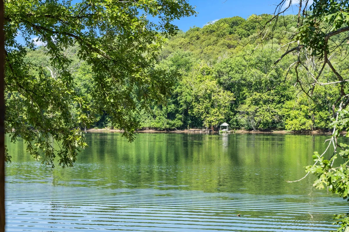 A tranquil lake scene with calm water, lush greenery along the shoreline, and a distant gazebo, evoking the peaceful and rejuvenating experience of a lakefront retreat.