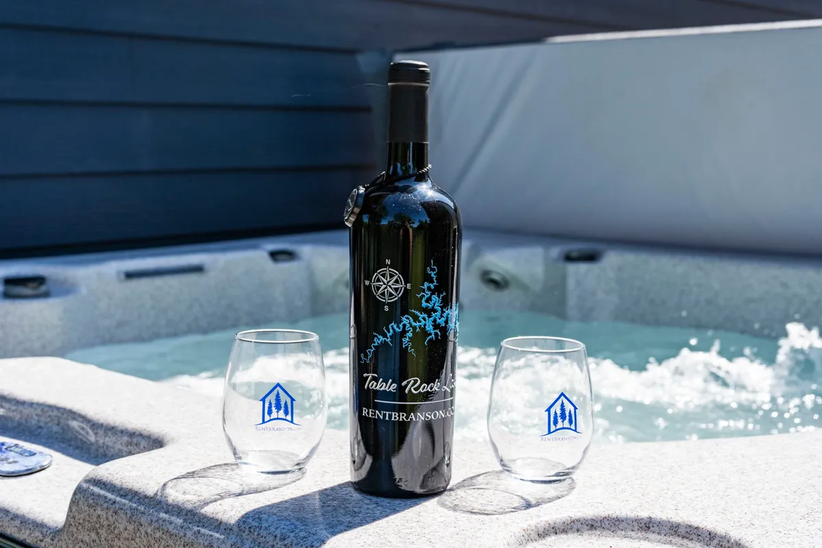 A close-up of the hot tub area, featuring a bottle of wine and two glasses, hints at intimate moments and celebratory relaxation. The bubbling water and inviting setup evoke the joy of unwinding together after a day by the lake.