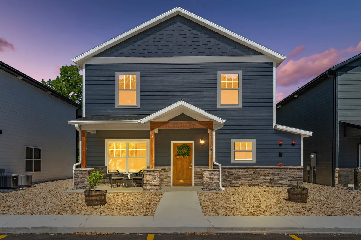 A welcoming front porch with stone accents, large windows, and a wreath on the door. The porch offers views ideal for relaxing, gathering with friends or family, and enjoying the transition between the vibrant exterior world and the private retreat.